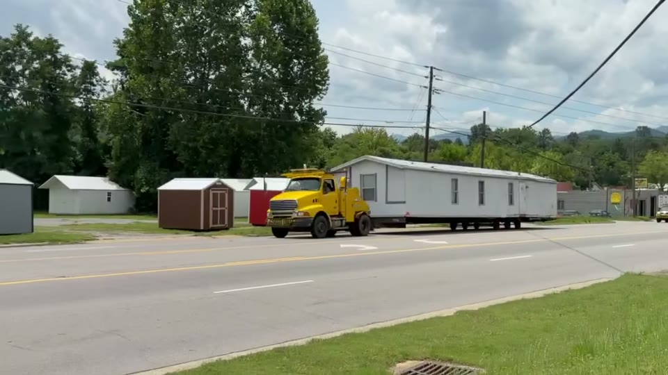 Our truck pulling a single-wide past the shops