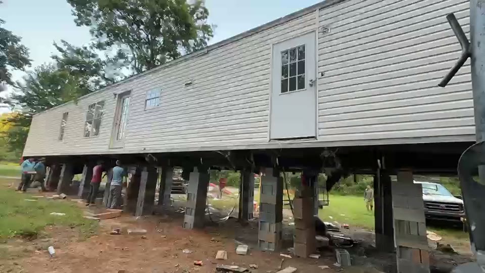 A double-wide raised on cribbing so it can be leveled